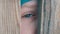 Unusual turquoise eye of a teenage boy full of tears looks through the doorway or a slot in the fence directly into the