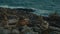 Unusual volcanic rock formations and a sea waves viewed from a cliff.