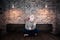 Unusual young man in comical mask sits alone on the bed in stylish apartment