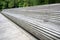 Unusually long park bench made of very long wooden decks with leafy trees behind it