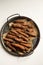 Unwashed carrots in a metal tray on a white background