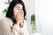 Unwell Asian woman hand covering nose sneezing, coughing having flu and allergic rhinitis with bad weather