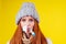 Unwell redhaired ginger woman runny nose wearing knitted sweater and scarf with many pills in hand in studio yellow