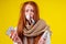 Unwell redhaired ginger woman runny nose wearing knitted sweater and scarf with many pills in hand in studio yellow
