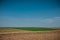 Unworked field with wheel tracks in spring near wheat land. Dirt texture with blue sky. Country dirt field texture.