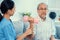 Unyielding senior patient doing physical therapy with the help of his caregiver.