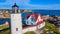 Up close aerial of lighthouse in Maine on island with town of homes in background