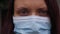 Up close face of a woman with blue eyes and a medical mask