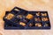 Up close view on a black tray for handcrafting with multiple sections filled with various kinds of amber and tools for crafting