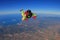 Up. Extreme people prefere sky sport. Fly men perfoms trick in air. Parachutist in green suit is in free fall. Skydiving