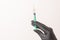 Up-filled syringe with a needle. The set holds a hand in black gloves.