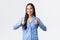Upbeat happy smiling asian girl in blue pajamas looking satisfied, showing thumbs-up in approval, saying well done or