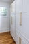 Updated white shaker cabinets with elegant gold sleek thin hardware in a newly renovated laundry room with hardwood