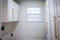 Updated white shaker cabinets with elegant gold sleek thin hardware in a newly renovated laundry room with hardwood