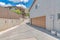 Uphill curved driveway beside the garage with sliding window and white texture bricks wall