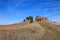 Uphill path to a stone church on top of a grassy hill against a blue sky