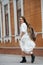 Uplifted woman walking out the street in white fluffy dress and heavy boots