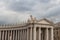 Upper facade of Peter`s Square Colonnade with rainy clouds on background, Vatican city state, Italy