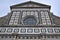 Upper part of the beautiful facade covered in white marble with black marble outline, of the church of Santa Maria Novella in Flor