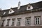 Upper part of a historic building in Vienna, simple but also elegant with six white windows and two dormers on the roof.