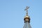 The upper part of the roof of the Orthodox Church with a cross against a blue cloudless sky