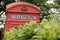 Upper section of red telephone box surrounded by trees