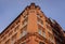 Upper stages of an old building made with red bricks with blue sky on background.