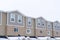 Upper storey of townhomes with snowy pitched roofs on a cold winter day