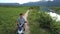 Upper view couple rides along track past river at farmland