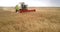 Upper view person operates machine reaping grain crops