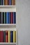 Upright format of a bookcase with colorful books in a white wall