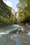 Upright photography of Running stream from Cascada de Sorrosal Sorrosal waterfall with autumn trees and river rocks in Broto