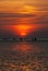 Upright view on people at the beach and watt in front of the setting sun.