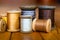 Upright Wooden Spools of Yellow, Gold, White, Silver and Dark Grey Thread and Resting Wooden Spool of Beige Thread on Wooden Plank