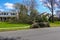 An uprooted fallen tree laying on the lawn in front of a house.