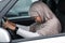Upset afro american lady in hijab driving car, bowed head and regrets about accident, suffers from pain after incident