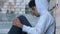 Upset Afro-American teen refugee holding knees, sitting in abandoned building