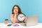 Upset anxious woman, office employee sitting at workplace, holding big clock and biting nails, working late hours