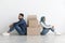 Upset arab family sitting separated by paper boxes on floor