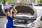 Upset Asian Korean woman in stress stranded on street suffering car engine failure having mechanic problem calling on mobile phone