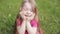Upset beautiful little cute girl crying on meadow surrounded by green grass medium close-up