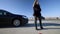Upset beautiful slim woman kicking road cone with blurred auto instructor standing at background. Dissatisfied Caucasian