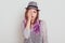 Upset beautiful woman with lilac hair wearing shirt and hat being sad, covering half of face with palm, keeps eyes closed,