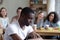 Upset black man sitting alone schoolmates scoffing him