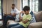 Upset boy sitting on sofa with father holding digital tablet at home