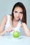 Upset brunette woman with green apple on a plate