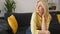 Upset depressed senior lady wearing yellow jumper sitting on sofa