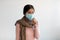 Upset despaired young indian lady in protective mask and scarf coughs, feeling bad and suffers from illness
