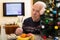 Upset ederly man sitting alone at home table at Christmas