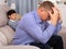 Upset father sitting after quarrel at home, son on background